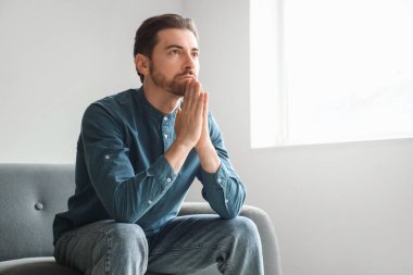 Sakallı adam evde dua ediyor.