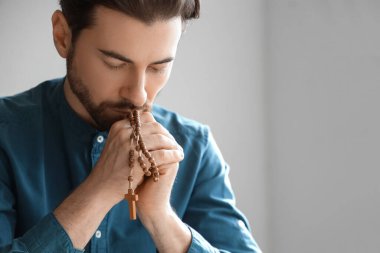 Tespihli bir adam evde dua ediyor.