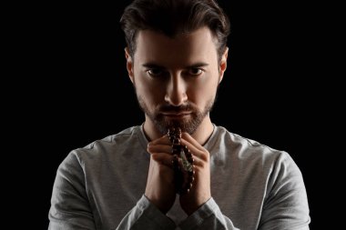 Dindar adam siyah arka planda dua ediyor.