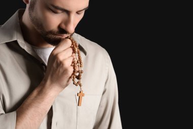 Dindar adam siyah arka planda dua ediyor.