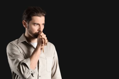 Dindar adam siyah arka planda dua ediyor.