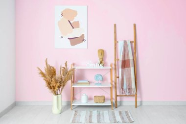 Raflar, merdiven, vazodaki otlar ve odadaki pembe duvarda resim.
