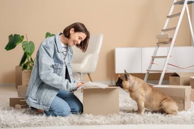 Fransız bulldog 'u olan güzel genç bir kadın paketini evde açıyor.