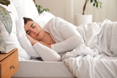 Genç adam evdeki rahat yatakta uyuyor.