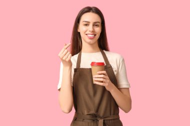 Kahveli genç bayan barista pembe arka planda kalp hareketi yapıyor.