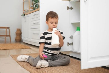 Mutfakta açık deterjan şişesi olan şirin bir çocuk. Tehlikedeki çocuk