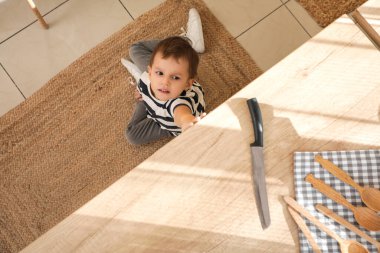 Mutfak tezgahında bıçağa uzanmaya çalışan şirin bir çocuk. Tehlikedeki çocuk