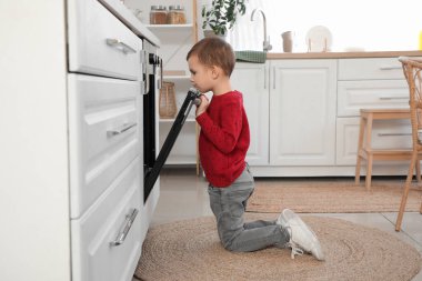 Küçük şirin çocuk mutfakta fırın açıyor. Tehlikedeki çocuk