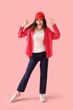 Pembe arka planda şapkayı gösteren güzel genç bir kadın.