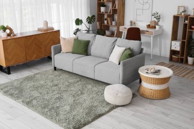 Gri kanepe, puf ve sehpası olan modern oturma odasının içinde.