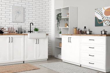 Mutfak tezgahında beyaz tuğla duvarın yanında.