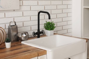 Mutfakta mutfak tezgahı ve lavabo beyaz tuğla duvarın yanında.
