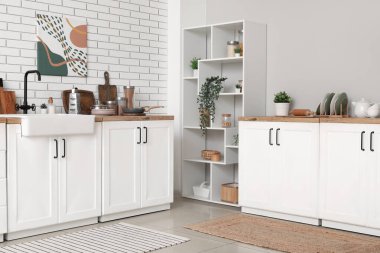 Raflar ve mutfak tezgahları beyaz tuğla duvarın yanında.