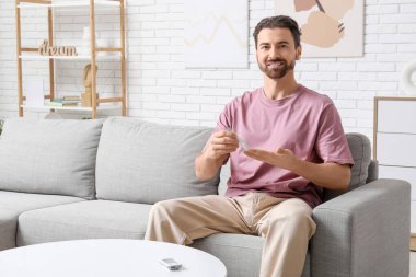 Şeker hastası genç adam evdeki kanepede tükenmez kalem kullanıyor.