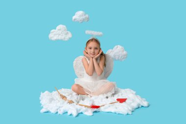 Aşk tanrısı gibi giyinmiş, ok ve yayla mavi arka planda bulutların üzerinde oturan tatlı küçük bir kız. Sevgililer Günü kutlaması