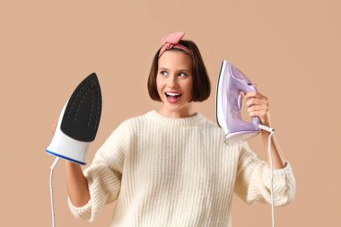 Bej arka planda iki prangalı gülümseyen genç kadın.