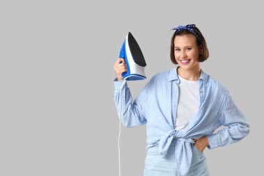 Gri arka planda demiri olan gülümseyen genç kadın.