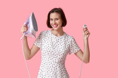 Pembe arka planda demir tutan gülümseyen genç kadın.