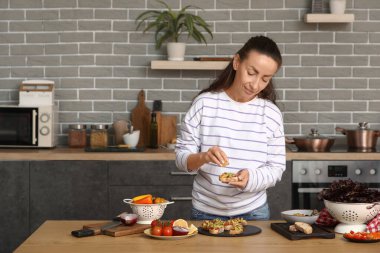 Güzel bir kadın mutfaktaki vegan bruschetta 'nın üzerine limon suyu sıkıyor.