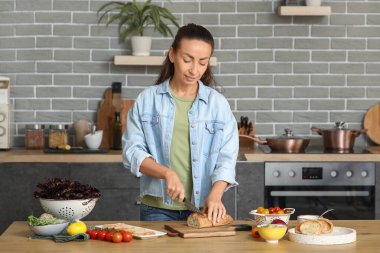 Mutfakta vegan bruschetta için ekmek kesen güzel bir kadın.