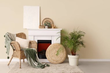 Odanın içi şömine ve battaniyeyle bej duvarın yanındaki hasır koltukta.