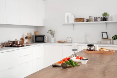 Ada masası, taze sebze ve çatal bıçaklı şık bir mutfak.