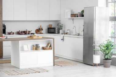 Modern buzdolabı ve ada masası olan şık bir mutfak.