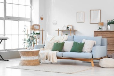 Gri kanepesi, kahve masası ve zeytin ağacı olan şık bir oturma odası.