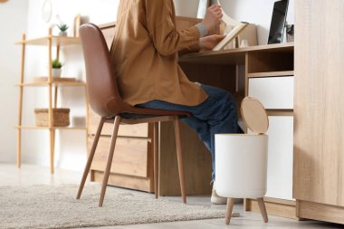 Çöp kutusuyla şık bir evde çalışan bir kadın.