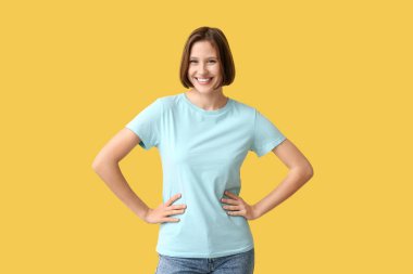 Sarı arka planda boş tişörtlü genç bir kadın.