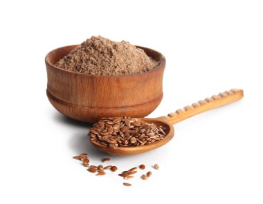 Bir kase keten unu ve beyaz arka planda tohumları olan tahta kaşık.