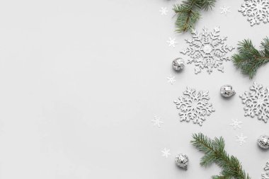 Gri arka planda Noel topları ve köknar dalları olan güzel kar taneleri