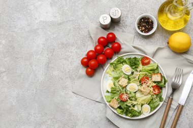 Lezzetli Sezar salatası, limon, yağ ve gri arka planda bir kase biber.