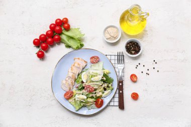 Lezzetli tavuklu Sezar salatası ve beyaz arka planda malzemeler.