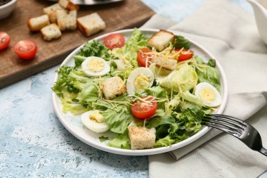 Mavi arka planda lezzetli Sezar salatası tabağı, yakın plan.