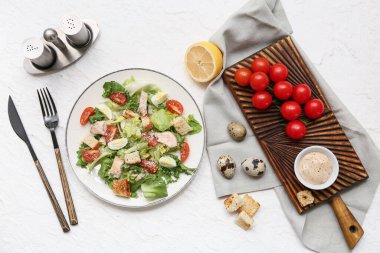 Lezzetli tavuklu Sezar salatası ve beyaz arka planda malzemeler.