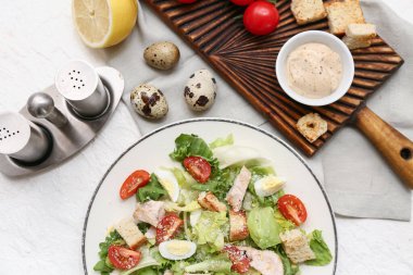 Lezzetli tavuklu Sezar salatası ve beyaz arka planda malzemeler, yakın plan.