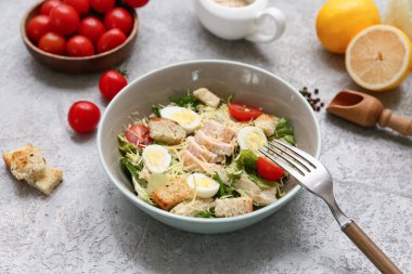 Lezzetli tavuklu Sezar salatası, domates ve limonlu gri arka plan.