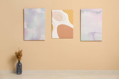 Çimenli vazo ve sanat galerisindeki bej duvarlı tablolar.