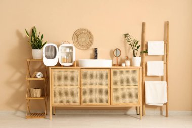 Lavabo, küçük buzdolabı ve kozmetik ürünleri banyodaki bej duvarın yanındaki çekmecelerde.