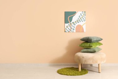 Yastıklı puf ve odadaki bej duvarda resim