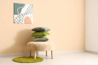 Yastıklı puf ve odadaki bej duvarda resim