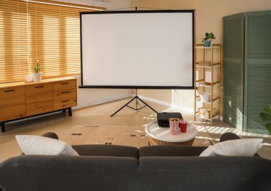 Gri kanepesi, patlamış mısırı ve kahve masasında modern projektörü olan şık bir oturma odası.