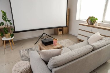 Gri kanepesi, patlamış mısırı ve kahve masasında modern projektörü olan şık bir oturma odası.