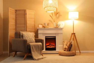 Şöminesi, koltuğu ve parlak lambaları olan rahat bir oturma odası.