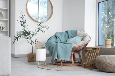 Koltuğu ve çöp kutusuyla aydınlık oturma odasının içinde.