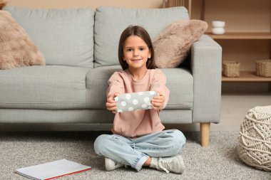 Kalem kutusu ve defteriyle evde oturan sevimli küçük mutlu kız.