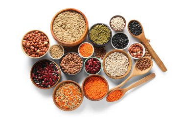 Beyaz arkaplanda farklı ham baklagillerden oluşan kaselerle kompozisyon