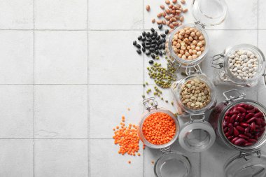 Açık fayans zemininde farklı baklagillerden oluşan cam kavanozlarla kompozisyon