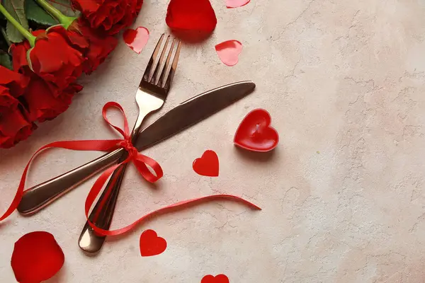 Sevgililer Günü için güzel çatal bıçak takımı. Kırmızı güller, mum ve bej arka planda kalpler.